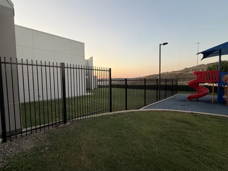 Ornamental steel fence line installed beside a Fort Worth, TX business at sunset